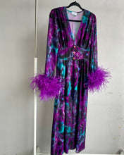 Carica l'immagine nel visualizzatore di Gallery, Abito maxi manica lunga elasticizzato in vita e bottoncini stile corsetto. Fantasia viola e petrolio acquarello, con boa in piuma di struzzo viola ai polsi. Spacco laterale. Attaccatura del boa tramite asoline e bottoncini cuciti a mano, per facilitare il lavaggio e per poterlo utilizzare anche senza piuma.