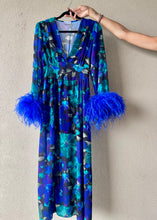 Carica l'immagine nel visualizzatore di Gallery, Abito maxi manica lunga elasticizzato in vita e bottoncini stile corsetto. Fantasia blu floreale, con boa in piuma di struzzo blu elettrico ai polsi. Spacco laterale. Attaccatura del boa tramite asoline e bottoncini cuciti a mano, per facilitare il lavaggio e per poterlo utilizzare anche senza piuma. Composizione tessuto: 50% polyester; 45% viscose; 5% elastam.