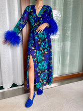 Carica l'immagine nel visualizzatore di Gallery, Abito maxi manica lunga elasticizzato in vita e bottoncini stile corsetto. Fantasia blu floreale, con boa in piuma di struzzo blu elettrico ai polsi. Spacco laterale. Attaccatura del boa tramite asoline e bottoncini cuciti a mano, per facilitare il lavaggio e per poterlo utilizzare anche senza piuma. Composizione tessuto: 50% polyester; 45% viscose; 5% elastam.