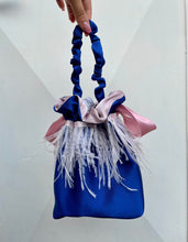 Carica l&#39;immagine nel visualizzatore di Gallery, Borsetta midi blu handmade in raso esterno con giro di piume di struzzo rosa cucito a mano e raso interno rosa; chiusura in raso con fiocco e manico arricciato. Perfetta per completare il tuo outfit da cerimonia. 
