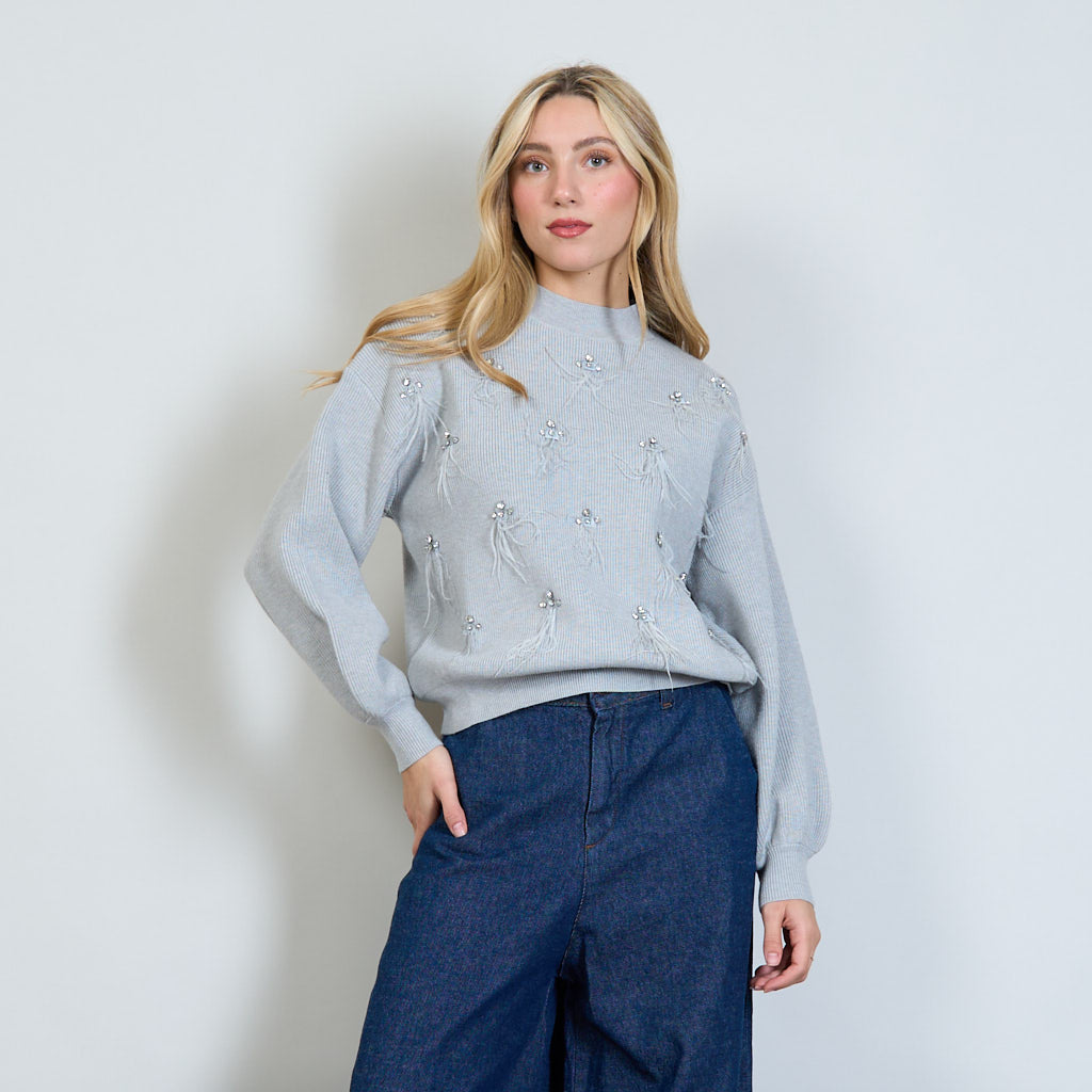 Maglione a maniche lunghe grigio a sbuffo, lavorato sul davanti con strass e piume. Collo finto. Taglia Unica.  Composizione tessuto: 50% viscose; 25% polyammide; 18% polyestere; 7% modal.