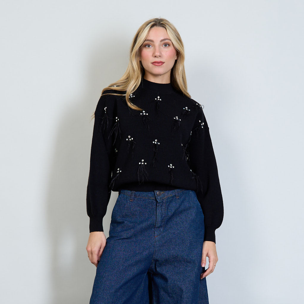 Maglione a maniche lunghe nero a sbuffo, lavorato sul davanti con strass e piume. Collo finto. Taglia Unica.  Composizione tessuto: 50% viscose; 25% polyammide; 18% polyestere; 7% modal.